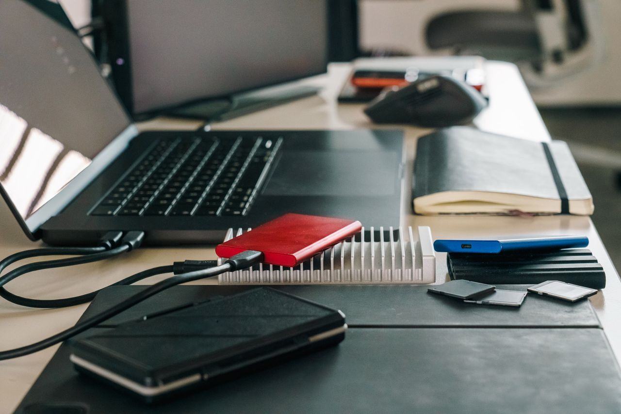 Modern office desk featuring laptop, external drives, and various tech accessories for efficient workflow.